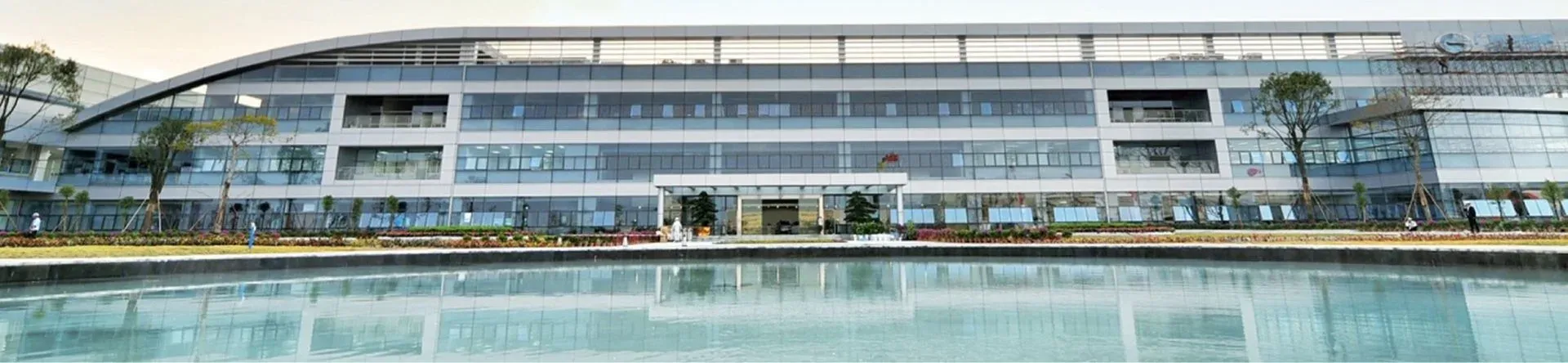 Edificio principal de la Fábrica Inteligente Ecológica de GAC AION, frente a un espejo de agua