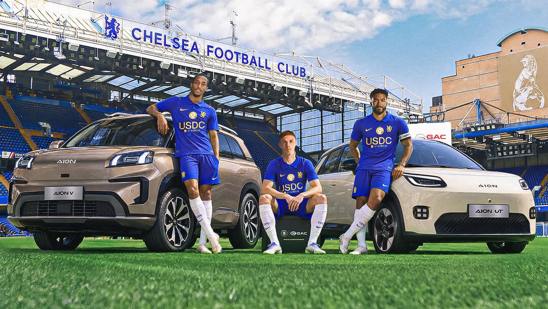 Tres jugadores del Chelsea FC en el césped de Stamford Bridge junto a un GAC AION V y un GAC AION UT